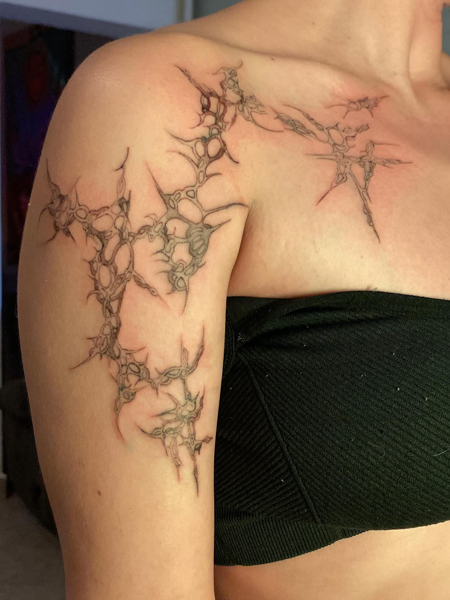 Ornamental crack network spreading across the collarbone and shoulder, fresh