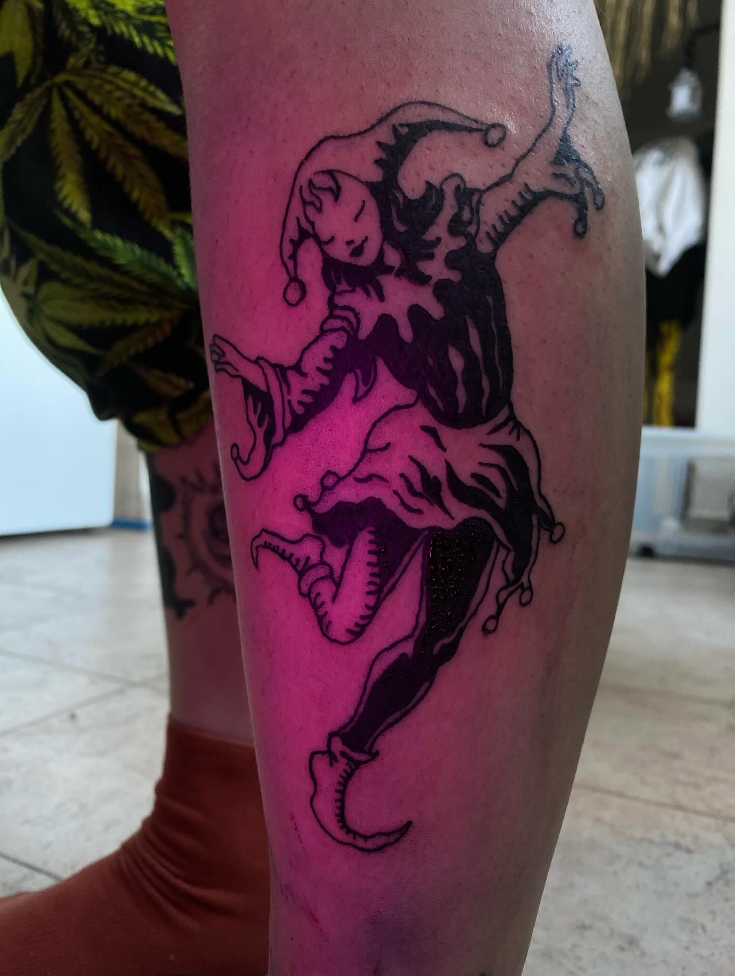 Jester blackwork on the calf under magenta light