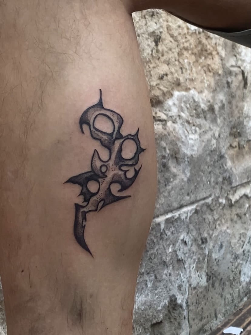 Perforated blade sigil on the calf, healed, shot against stone